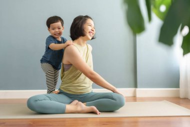 Asyalı kadın ve genç çocuk paspasın üzerinde kaliteli zaman geçiriyorlar, oyun ve içerde nazik hareketler yapıyorlar..