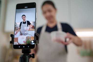 Asyalı kadın içerik yaratıcısı cep telefonuyla yemek pişirme videosu kaydetti, çevrimiçi vlog 'unun bir parçası olarak ev yapımı yemek ve yaşam tarzı ipuçlarını paylaştı.