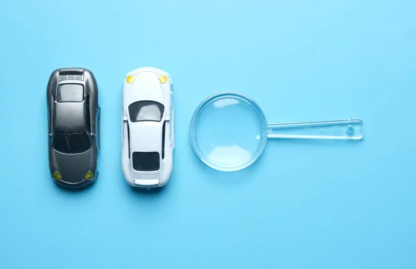 Flatlay picture of two miniature cars with magnifying glass insight. Best car deal concept.