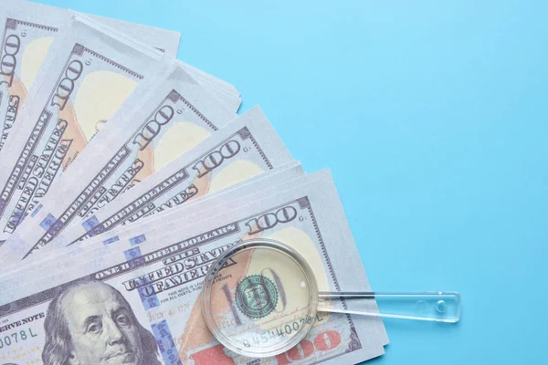 Telif uzayı arka planında büyüteçle sahte para çekilmiş düz bir resim. Mali çözüm kavramı.