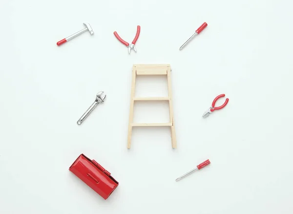 stock image A flatlay picture of ladder with tools miniature on white background. Uner maintainence concept