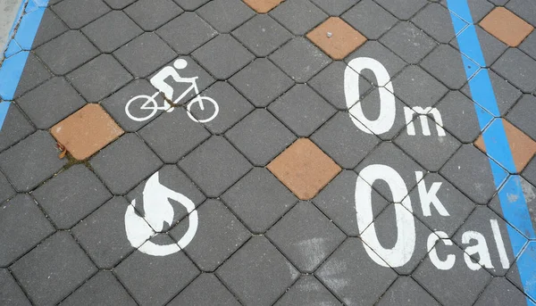 A picture of bicycle sign with distance and calorie burn marking on the pavement.