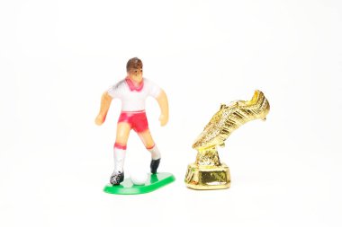 Minyatür altın çizmeli, futbolcu minyatürlü beyaz arka planda altın öngörülü..