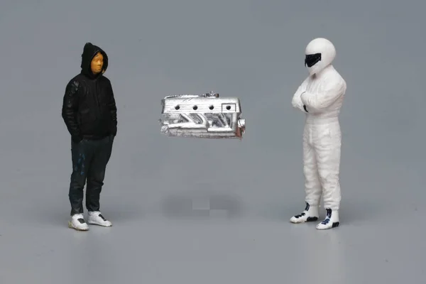 A picture of miniature engine and 2 men discussion on gray background. Vehicle engine and performance analysis