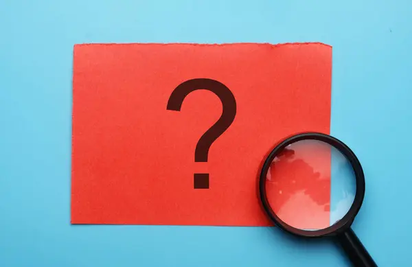 A picture of red paper with question mark and magnifying glass.