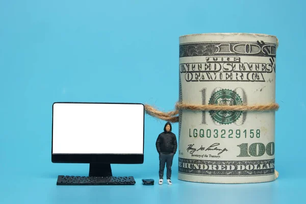 A picture of desktop, men miniature and fake money on blue background. Internet and money growth.