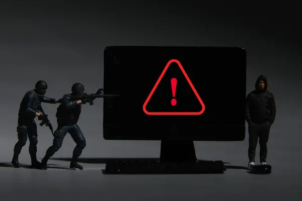 A picture of miniature anti terrorist and men in hood with warning sign at miniature computer