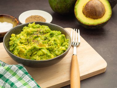Avokado, limon, tuz ve biber gibi ev yapımı guacamole malzemeleriyle ahşap bir tahtanın üzerine konmuş taze guacamole. Üst Manzara. Geleneksel Meksika hazırlığı kavramı.