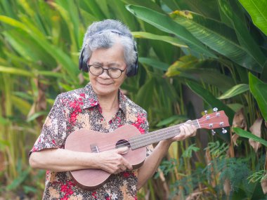 Kısa gri saçlı, gözlüklü, gülümseyen ve bahçede dikilirken gitar çalan neşeli bir son sınıf öğrencisi. Yaşlılar ve rahatlama kavramı.