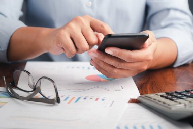 Çizelgeyle akıllı bir telefonu tutarken yakın plan, iş için grafik raporu. Mesaj için yer var. İş, finans, planlama ve iletişim kavramı.