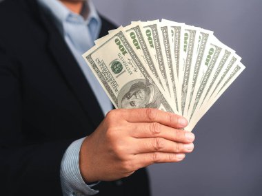 Bir stüdyoda dururken Amerikan banknotlarının el ele tutuştuğu bir iş adamı. Yakın plan fotoğraf. İş ve finans kavramı.