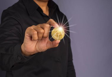 Yatırımcı adam güneş ışığıyla birlikte bir bitcoin altın para gösteriyor. Yakın plan fotoğraf. Mesaj için yer var. Sanal kripto para birimi ve gelecekteki para kavramı.