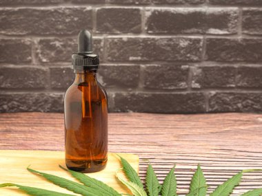 Kenevir yağı, eski tuğla duvar zeminli bir tahta kesme tahtasına yerleştirilmiş bir kavanozda bulunuyor. Mesaj için yer var. Tıbbi ve iş konsepti için marihuana tarlası.