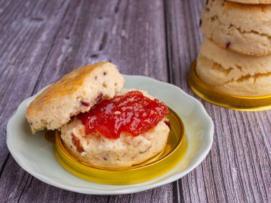 Geleneksel İngiliz usulü çörekler taze ev yapımı, ahşap bir masada çilek reçeli. Yakın plan fotoğraf. Tatlı, içecek ve rahatlama konsepti..