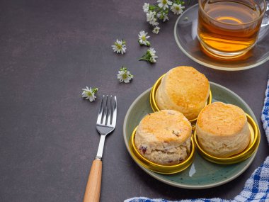İngiliz usulü çörekler taze pişmiş ev yapımı çörekler ve eski mutfak masasında bir çay fincanı ve bir tepside çilek reçeli. Mesaj için yer var. Tatlı ve içecek konsepti.
