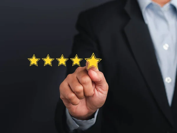 stock image Businessman pointing five-star symbol to increase the rating of the business against a gray background. Customer feedback and experience concept.