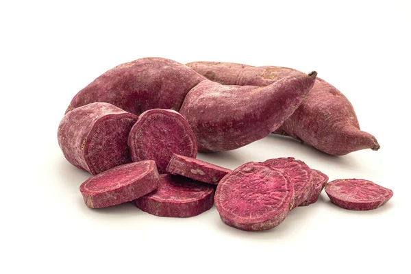 stock image Pile of purple yams or purple sweet potatoes whole and sliced on a white background. Side view. Vegan fruit and healthy fruits concept.