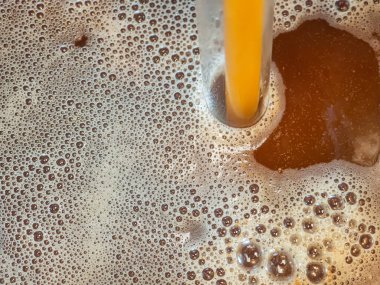 Bira ve köpüğü fermantasyon kabına yakın çekim. Malttan ev birası yapma süreci. Arpa ve koyu malttan bira..