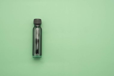 Essential oils in a bottle placed on a green background. Space for text. Top view photo.