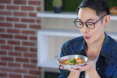 Genç adam tavada yumurta, jambon ve sebzeyle kahvaltıya bakıyor. Kahvaltı için basit bir yemek. Sağlıklı gıda konsepti.