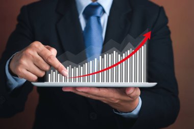 İş adamı tableti tutuyor ve okun havada olduğu bir istatistik grafiği gösteriyor. Borsa yatırımları fonları ve dijital varlıklar. İş finans teknolojisi ve yatırım kavramı.