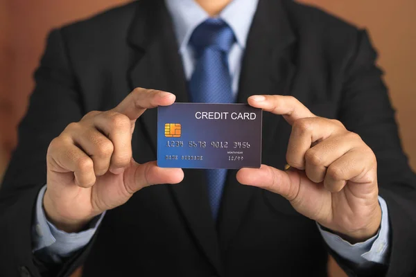 Podnikatel Držící Makléřskou Modrou Kreditní Kartu Zatímco Stojí Hnědým Pozadím — Stock fotografie