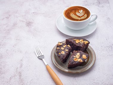 Tabakta brovniler ve beyaz bir kahve fincanı. Yan görüş. Lezzetli çikolatalı turta. Tatlı, içecek ve rahatlama konsepti..