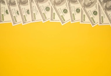 Sarı arka planda izole edilmiş 100 dolarlık banknotların en üst görüntüsü. Düz yatıyordu. Mesaj için yer var. Amerikan para birimi, iş ve finans kavramı.
