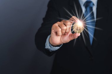 Bir iş adamının elinde gri arka planda güneş ışığı etkisi olan bir bitcoin bulunur. Mesaj için yer var. Gelecek para kavramı ve sanal kripto para birimi.