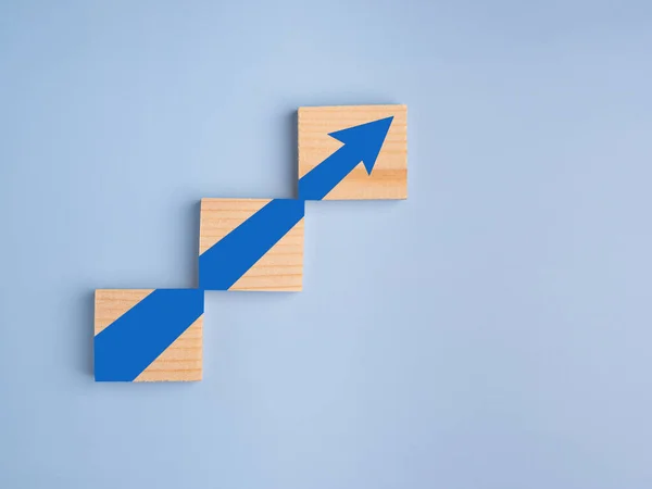 Wood blocks with arrows up. Business growth or increasing concept picture, the rising arrow on wooden blocks laid on a light blue background. Business and strategy concept.