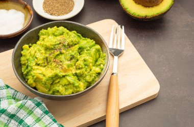 Tahta kesme tahtasına konmuş taze guacamole ev yapımı avokado, limon, tuz ve biber karışımı. Üst Manzara. Geleneksel Meksika hazırlığı kavramı.