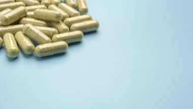 Andrographis 'in düz uzanmış panikleme kapsülleri açık mavi arka planda izole edilmiş. Mesaj için yer var. Bitkisel, ilaç ve sağlık hizmetleri kavramı.