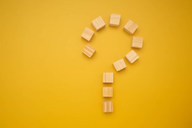 Tahta blokların sıralanması ile ilgili soru işareti kavramı metin için alanı olan izole edilmiş sarı arkaplan.