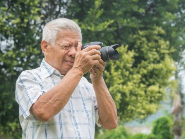 Dışarıda dikilirken dijital kamerayla fotoğraf çeken mutlu kıdemli bir adam. Yaşlanmış insanlar fotoğrafçı ve rahatlama konsepti.