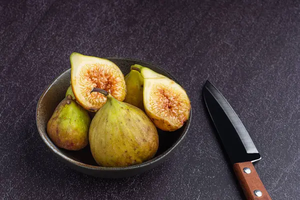 Figs fruit on a bowl and knife are on a stone table with space for text. High Vitamins fruit. Healthy fruits and health care concept.