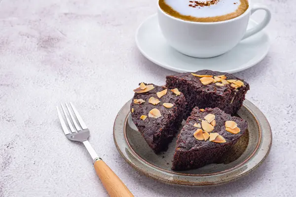 Tabakta taze browni parçaları ve beyaz bir kahve fincanı. Yan görüş. Lezzetli çikolatalı turta. Tatlı, içecek ve rahatlama konsepti..