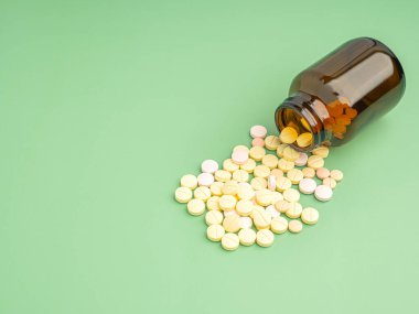 Açık yeşil arka planda izole edilmiş ilaç şişesinden dökülen tıbbi haplar. Üst Manzara. Mesaj için yer var. İlaç ve tedavi kavramı.