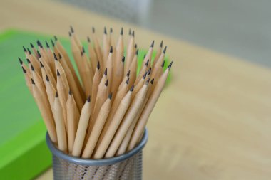 Birçok kurşun kalem ahşap bir masanın üzerindeki ağ kutusunda. Mesaj için yer var. Yakın plan fotoğraf..