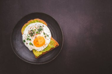 Avokado ve yumurtalı tost tabakta servis edilir. Üst Manzara. Metin için boşluk.