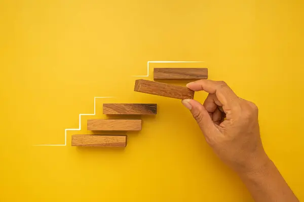 手拿着空木块 安排堆成黄底隔离的阶梯 业务增长和成功进程概念 — 图库照片