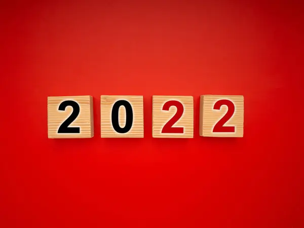 Happy New Year 2022 on wooden cubes isolated on a red background. The business growth process for goal. Christmas and Happy New year.