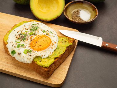 Tahta kesme tahtasının üzerinde avokado ve yumurtalı tost. Üst Manzara. Metin için boşluk.