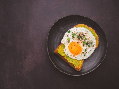 Avokado ve yumurtalı tost tabakta servis edilir. Üst Manzara. Metin için boşluk.