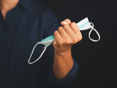 COVID 19 salgınının sonu. Normal hayata geri dönmek için tecrit sona erdi. Adamın eli yumruklarında tıbbi maske tutuyor. Zafer el maskesi. Salgın Coronavirus hastalığının sonunun sembolü..