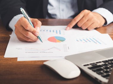 Ofiste çalışırken kağıt imzalamak için elinde kalem tutan takım elbiseli bir iş adamı. Yakın plan fotoğraf. İş konsepti.