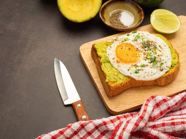 Tahta kesme tahtasının üzerinde avokado ve yumurtalı tost. Üst Manzara. Metin için boşluk.