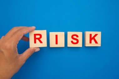 Risk yönetimi konsepti. Tahta küplerin mavi arka planda izole edilmiş 