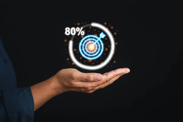Targeting and achieving a goal in business concept. Digital image of target icon progress for business achievement on the palm of a businessman while standing with black background in the studio.