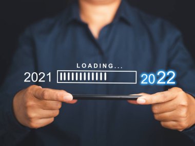 2022 'ye geri sayım. 2021 'den 2022' ye kadar bir cep telefonunun üstündeki sanal ekranda yükleme yap. Mutlu Noeller ve mutlu yıllar. Akıllı telefon tutan bir iş adamının yakın çekimi..