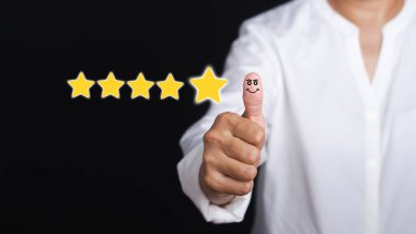Müşteri memnuniyeti için en iyi hizmet beş yıldızlı not veriyor. Müşteri geribildirimi, hizmet değerlendirmesi, deneyim ve tatmin kavramı. Gülen yüz simgesi için baş parmağınızı kaldırın..